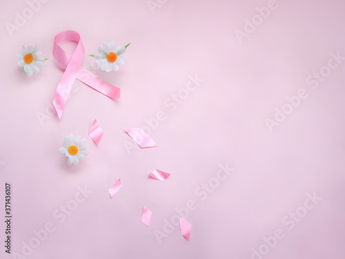 Breast cancer awareness pink ribbon with daisy flower on pink background, october symbol, healthcare and medicine concept © Stella