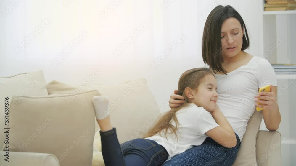 4k video of mother and daughter lying on sofa and watching something in the phone. 4k video of mother and daughter lying on sofa and watching something in the phone.