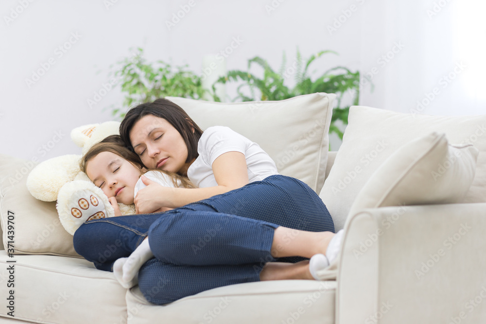 Photo of mom and daughter hugging and sleeping on sofa.
