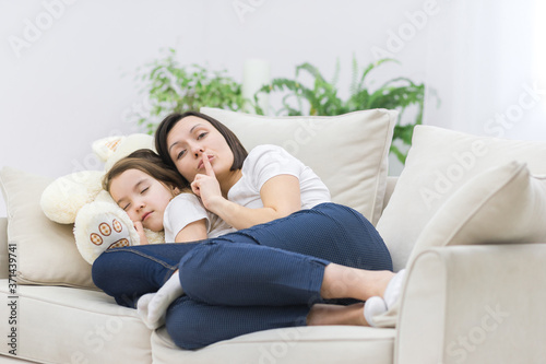 Photo of mom showing silence sign while her daughter sleeping.