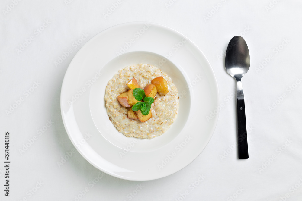 Oatmeal porridge with baked apple in white bowl