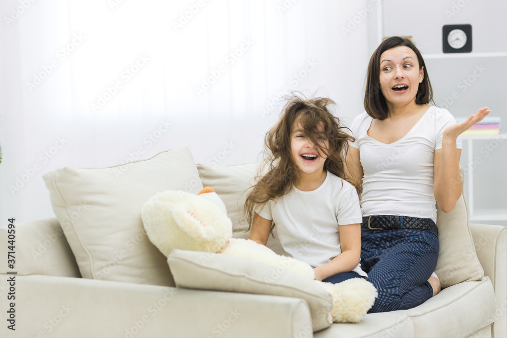 Photo of little girl with messy hair and her mother beside.