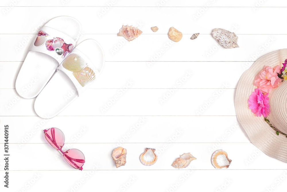 White wooden background with flip flops, seashells and straw hat