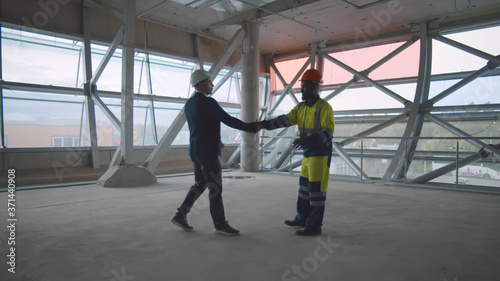 Architect and businessman handshaking greeting at construction site