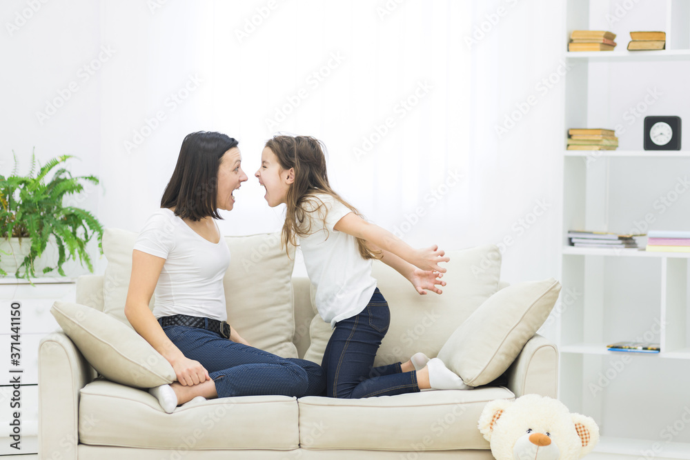 Photo of mother and daughter sitting playing on sofa. Photo of mother and daughter sitting playing on sofa.