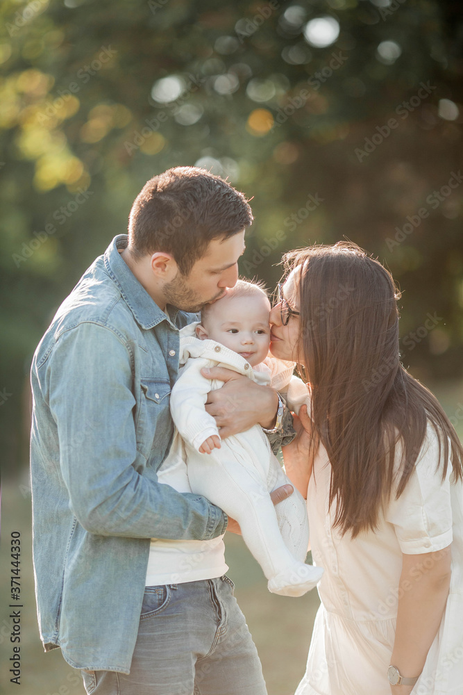 Young beautiful family walks in the park. Family portrait in the sunset light. Summer picnic. Young beautiful family walks in the park. Family portrait in the sunset light. Summer picnic.