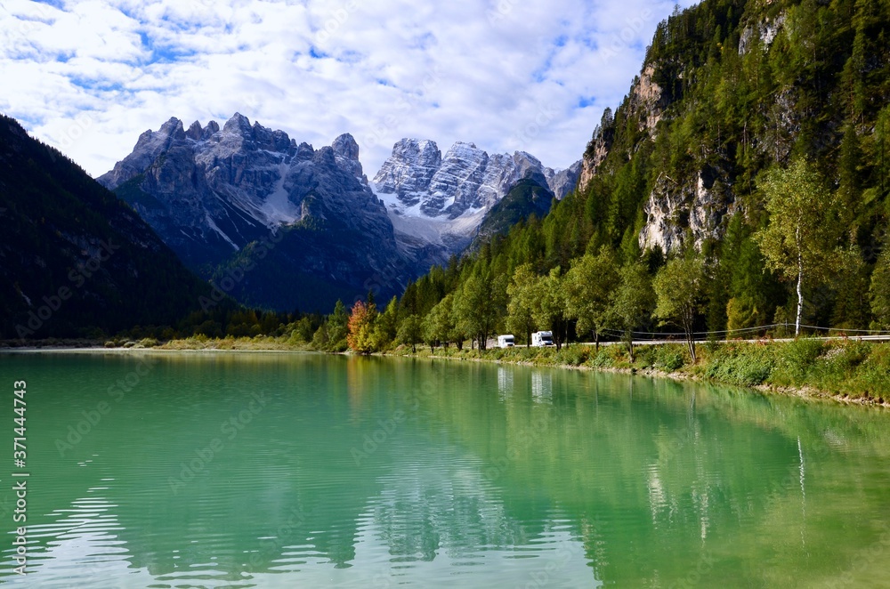 Dolomites mountains(Monte Cristallo) in South Tirol, Italy,emerald colored lake Duerrensee(Landro)in front,reflections on the water surface,autumn landscape,blue sky with clouds background,a sunny day