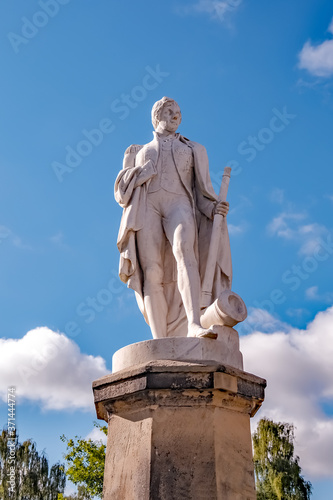 An old and undientifiable statue figurine captured against a bright blue sky on a summer's day.
