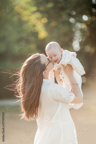 Young beautiful family walks in the park. Family portrait in the sunset light. Summer picnic. photo