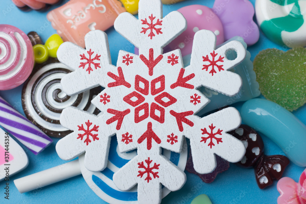 Snowflake toy on candy background close-up top view
