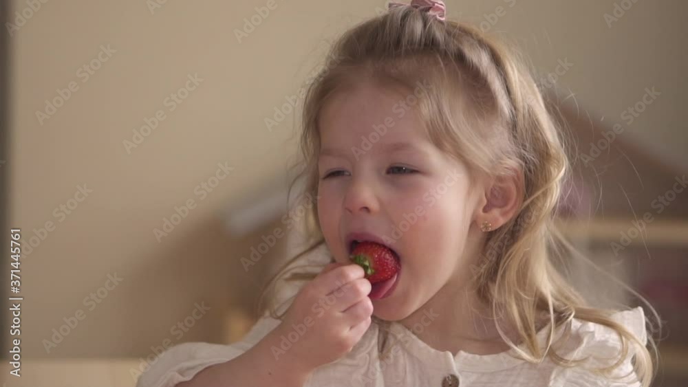 Happy child eating strawberries. The girl is eating a berry. Healthy food for children. Laughter and joy. High quality FullHD footage Happy child eating strawberries. The girl is eating a berry. Healthy food for children. Laughter and joy. High quality FullHD footage