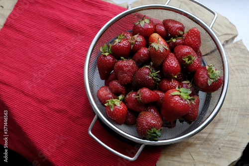 Fresh strawberries in an iron sieve on a wood. 