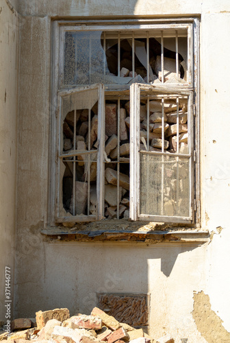 Image of a damaged and collapsed window within an old building with a pile of bricks