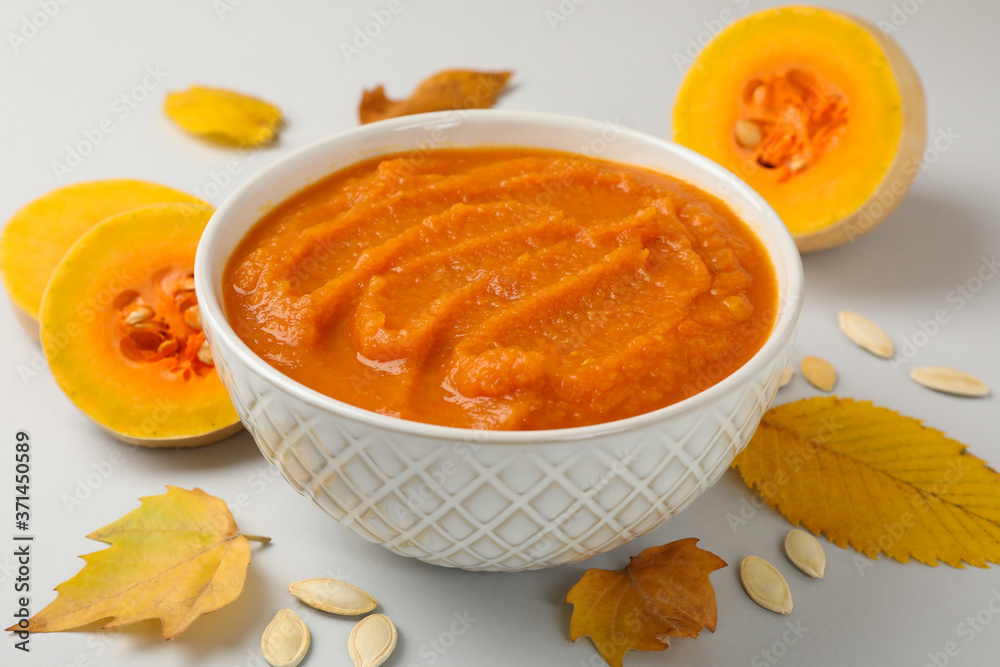 Composition with bowl of pumpkin puree on gray background, close up Composition with bowl of pumpkin puree on gray background, close up