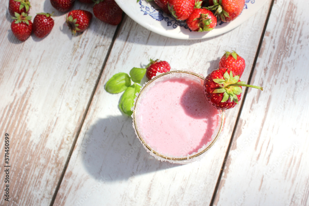 Strawberry milkshake or smoothie on white wooden table with fresh strawberries at the background. Top view. Strawberry milkshake or smoothie on white wooden table with fresh strawberries at the background. Top view.