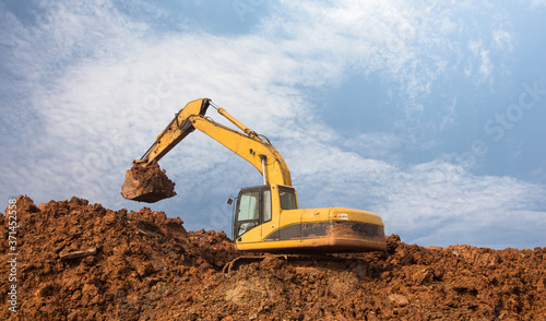 Large yellow excavator digging on the mound