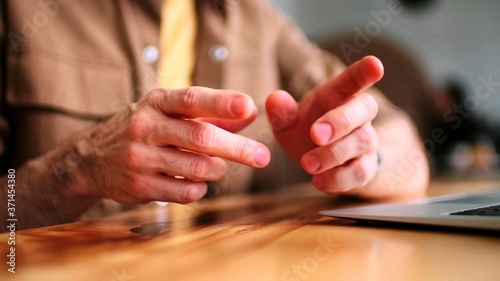 A close-up of the gestures of a man next to a laptop