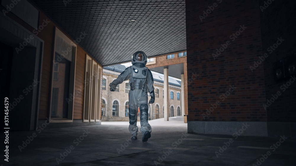 Low Angle Shot of a Confident Handsome Astronaut is Walking Towards the Camera in a Neighbourhood with Modern Scandinavian Buildings. Man in Futuristic Suit with Technological Panel on His Hand. Low Angle Shot of a Confident Handsome Astronaut is Walking Towards the Camera in a Neighbourhood with Modern Scandinavian Buildings. Man in Futuristic Suit with Technological Panel on His Hand.