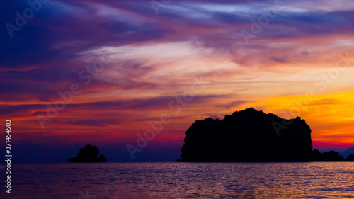 A beautiful setting sun behind the silhouette hills and rocks with its reflection over the sea waves at Tanjung Rhu Beach, Langkawi, © Shibin