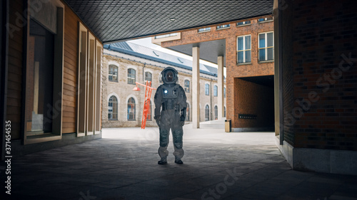 Low Angle Shot of a Confident Handsome Astronaut is Stands in a Neighbourhood with Modern Scandinavian Buildings. Man in Futuristic Suit with Technological Panel on His Hand. © Gorodenkoff