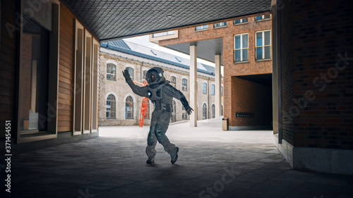 Handsome Man in Spacesuit is Dancing in a Neighbourhood. Astronaut is Happy and Makes Creative Robotic Moves. Successful Spaceman in White Futuristic Suit with Technological Panel on His Hand.