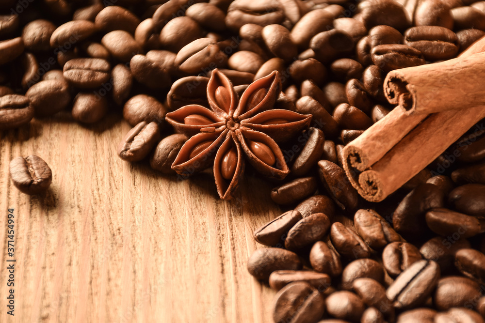 Fototapeta Anise, cinnamon and a lot of coffee beans lie on a wooden table. There is an empty space at the bottom left.