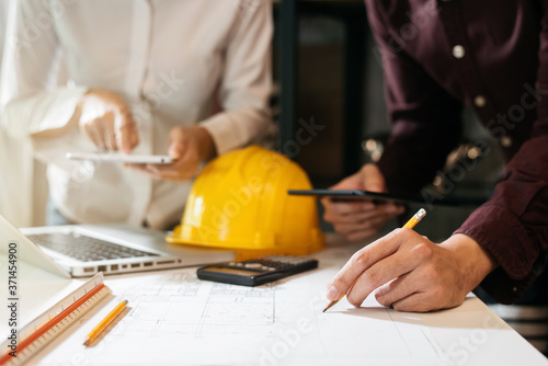 Businessman working as a team discussing data working and tablet, laptop with on on architectural project at construction site at desk in office.