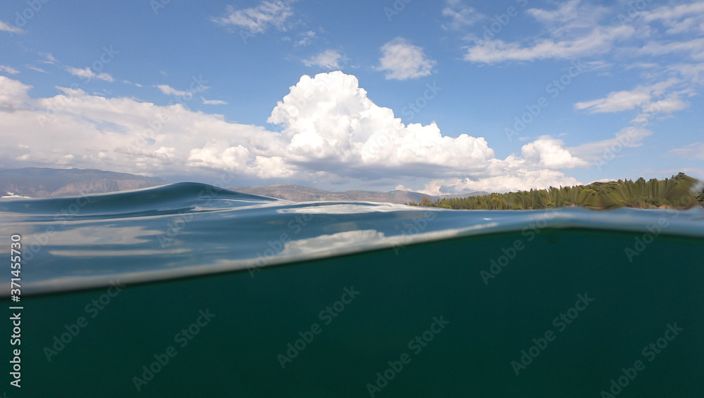 Split underwater photo of exotic Caribbean island seascape with emerald sea and beautiful clouds