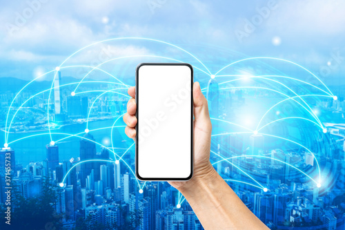Hand holding blank screen smartphone with digital technology connection city background