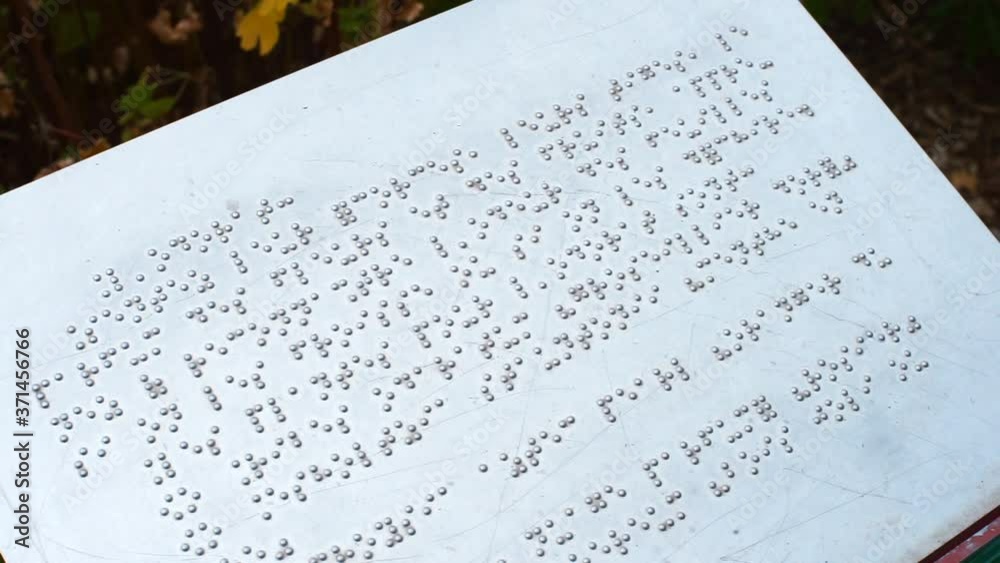 Metal plate describing a tourist attraction in a braille font. Raised