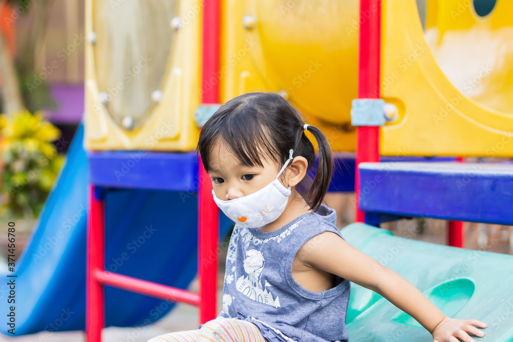 Portrait image of 2-3 yeas old baby. Happy Asian child girl smiling and wearing fabric mask,​ She playing with slider bar toy at the playground, social​ Distance,​ Learning and active of kids concept.