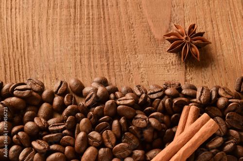 Sprinkled coffee beans at the bottom of the photo, as well as anise and cinnamon. Top photo of empty wood background