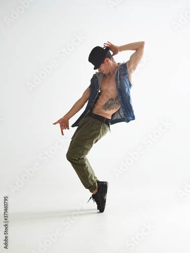 Wall Mural Stylish young guy breakdancer in hat dancing moonwalk in studio isolated on white background