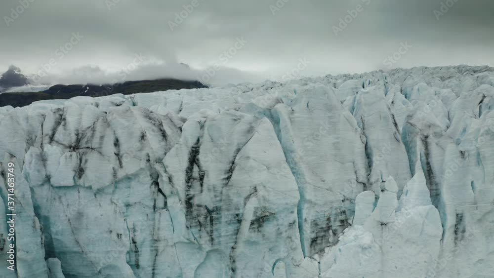 Aerial: Close up of Largest Glacier in Europe Vatnajokull Iceland Cloudy Gloomy day. Ridges with black ash. Melting ice. Concept of global warming