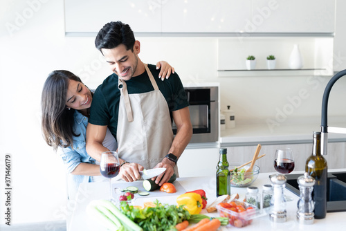 Smiling Hispanic Couple Preparing Food At Home