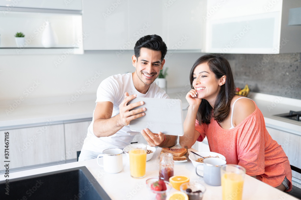 Couple Looking At Tablet Computer During Breakfast