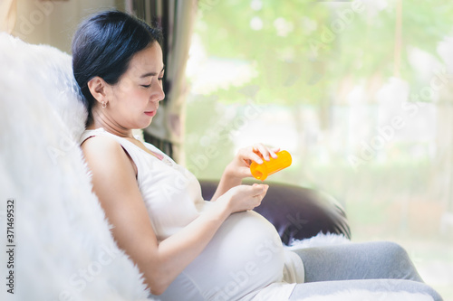 Slika na platnu Close up of asian pregnant woman is taking the the pill from the bottle, concept of healthcare ,risk and precaution of use the medicine in pregnancy woman and risk to the baby and rational drug use