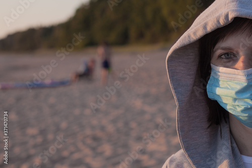 Young woman in a medical mask on the beach. Life after the coronavirus pandemic, travel and vacation at sea
