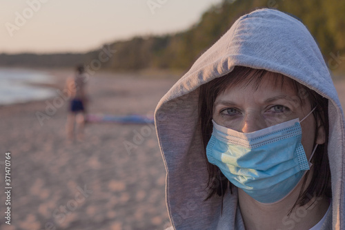Young woman in a medical mask on the beach. Life after the coronavirus pandemic, travel and vacation at sea