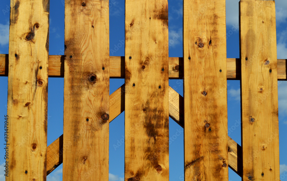 Ocher wooden fence. Clear summer sky. Solar lighting Ocher wooden fence. Clear summer sky. Solar lighting