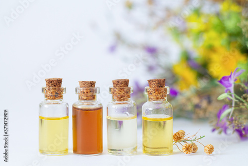 Bottles with organic essential aroma oils on wildflowers and dried herbs background