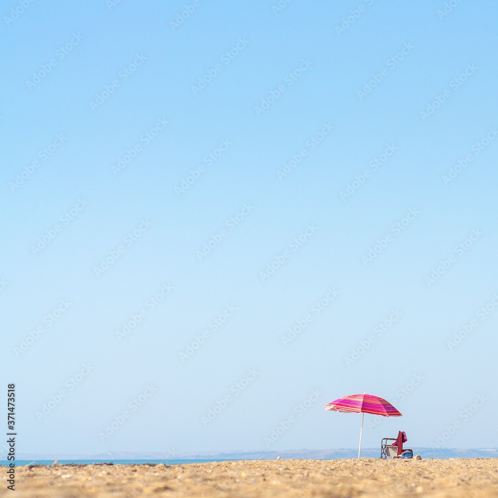 red umbrella on the beach with yellow sand and blue sky