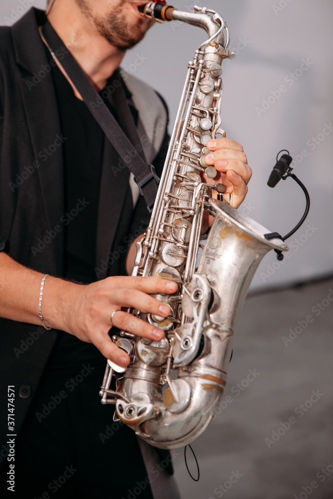 Fototapeta premium A musician at the event plays the saxophone. Сlose-up of hands and tools