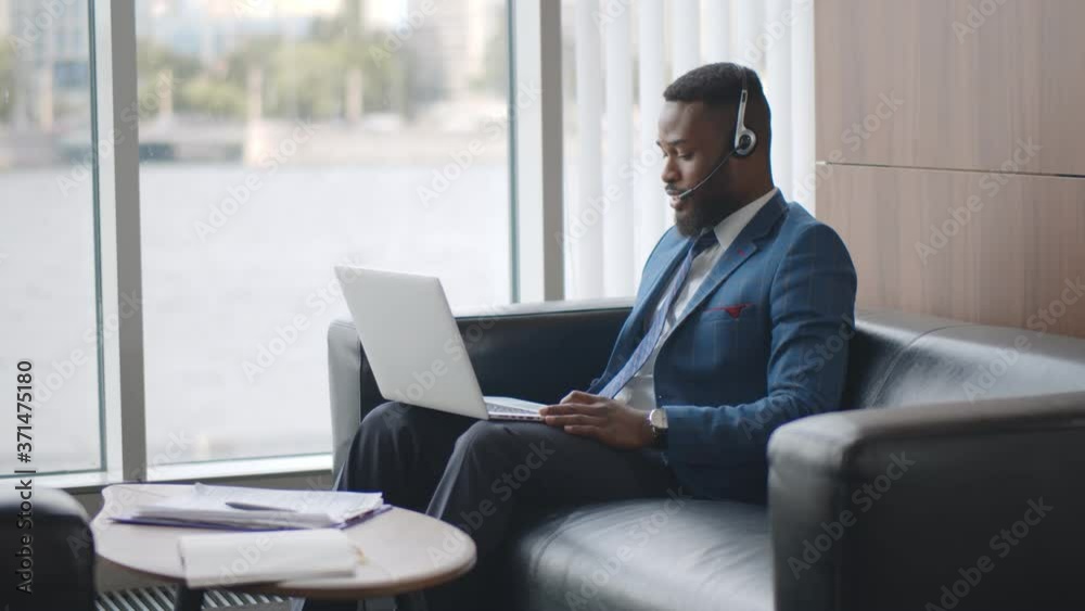 Young african businessman in headset having video conference with client on laptop Young african businessman in headset having video conference with client on laptop