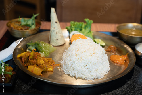 Photography Indian metal plate with rice, chicken and pita bread