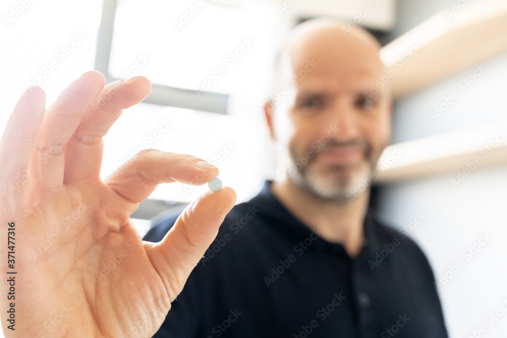 Selective focus on the hand of a man holding a pill