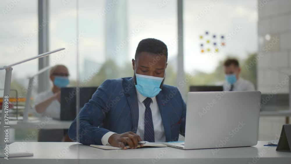 African worker wearing face protective mask using laptop computer working at office