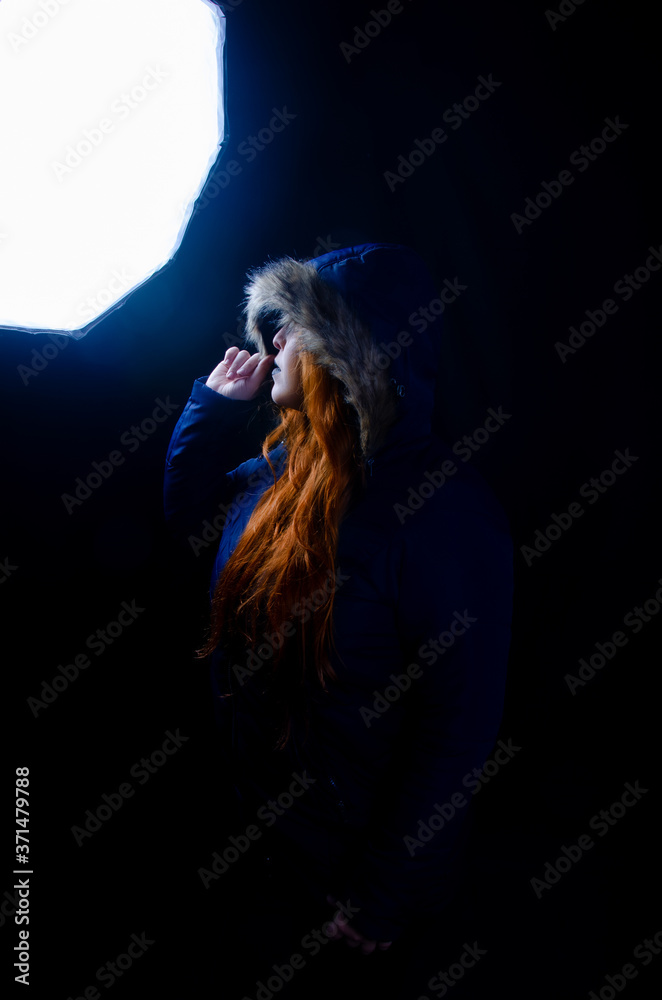 Portrait of a redhead with coat made in studio, low key image, with black background.