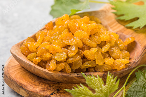 Golden raisins or sultana in bowl on stone background. Dried fruit, healthy snack food