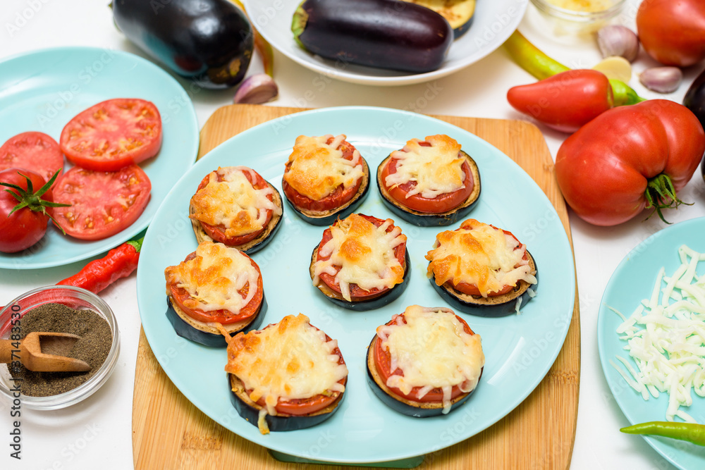 cooking homemade vegan pizza eggplant bites, tomatoes, peppers, mozzarella on a blue plate. eggplant stacked on a light background cooking homemade vegan pizza eggplant bites, tomatoes, peppers, mozzarella on a blue plate. eggplant stacked on a light background